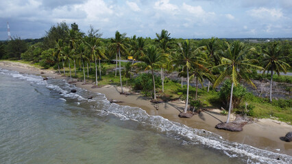 Aerial view of ocean waves rolling onto a beautiful beach with pink sand at sunrise. Sandy coastline with turquoise ocean waves. Gentle ocean waves on