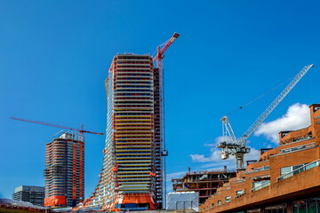 Large construction site with construction cranes, new high-rise buildings under construction on the background of blue cloudy sky background