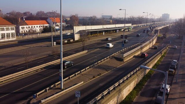 Traffic moves across &Aacute;rp&aacute;d Bridge in Budapest during sunset with golden haze and city glow