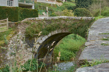 Historic granite and slate bridge from Camino Real connecting both riverbanks in the Os Muiños...