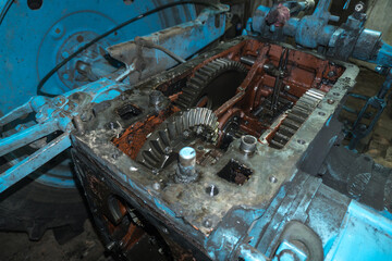 repair of an old blue tractor in a vintage garage, dismantling and installation of a gearbox, replacement of bearings