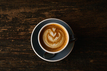 Hot coffee latte with latte art milk foam in cup mug on wood desk on top view. As breakfast In a coffee shop at the cafe,during business work concept,vintage style