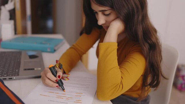 Young student highlighting text in document at home