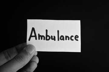 Hand holding a paper card with the word AMBULANCE