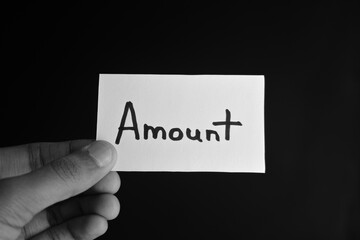 Hand holding a paper card with the word AMOUNT