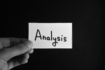 Hand holding a paper card with the word ANALYSIS