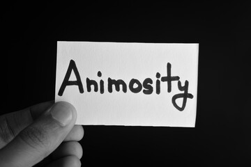 Hand holding a paper card with the word ANIMOSITY
