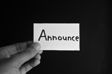 Hand holding a paper card with the word ANNOUNCE