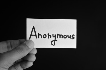 Hand holding a paper card with the word ANONYMOUS
