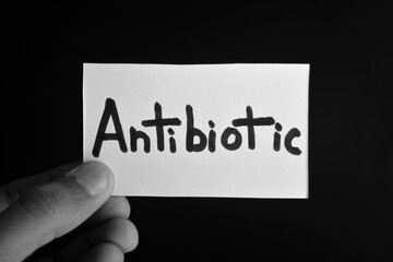 Hand holding a paper card with the word ANTIBIOTIC