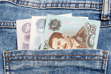 Old Iraqi Dinar in the pocket of blue jeans