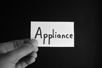 Hand holding a paper card with the word APPLIANCE