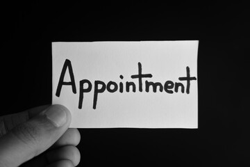 Hand holding a paper card with the word APPOINTMENT