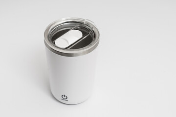 Isolated silver steel can opener bearing down on a metallic tin can