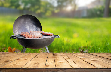 summer time in backyard garden with grill BBQ, wooden table, blurred background