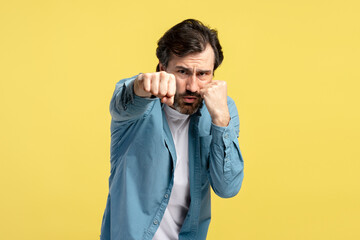 Determined man throwing punches on yellow background