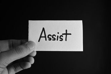Hand holding a paper card with the word ASSIST