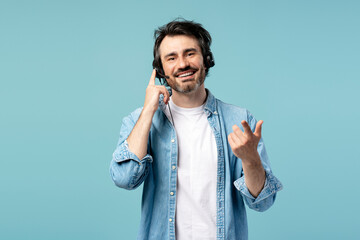Smiling male call center agent wearing headset assisting customer on blue background