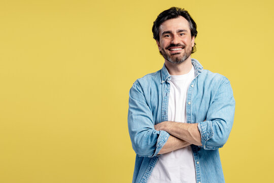 Portrait of smiling man with crossed arms on yellow background