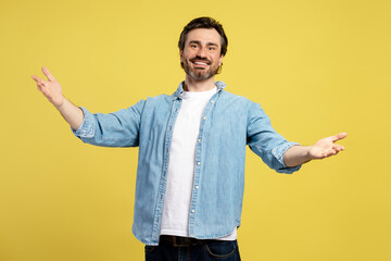 Smiling man opening arms and welcoming on yellow background