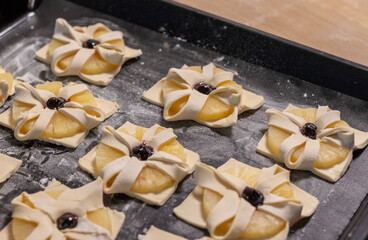 Puff pastry with pineapple wedges wrapped and cherry on top, on the baking tray in the kitchen...