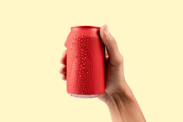 Male hand holding a red aluminium drinking soda can mockup isolated on yellow background