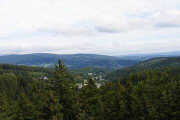 a scenic vista overlooking a dense evergreen forest covering rolling hills and a small town nestled...