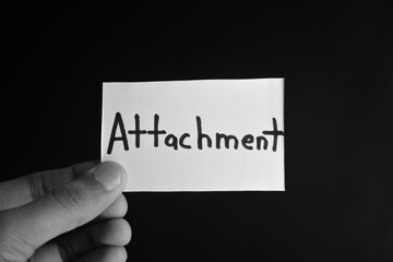 Hand holding a paper card with the word ATTACHMENT