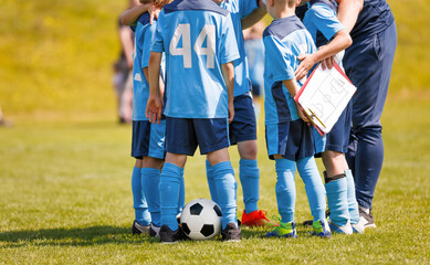 Football players in a circle huddling with a coach during time break. Coach holding tactics...