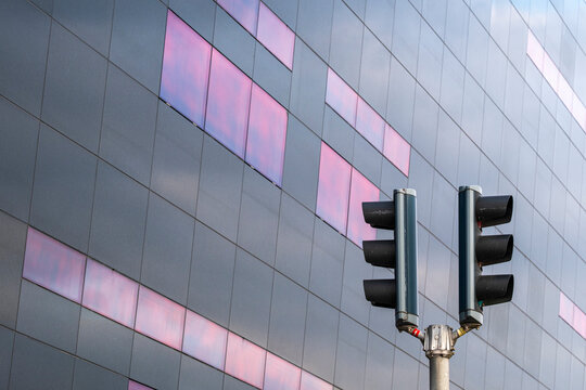 Traffic lights mounted on wall with reflective glass panels, Copenhagen urban architecture with geometric background and signaling infrastructure.