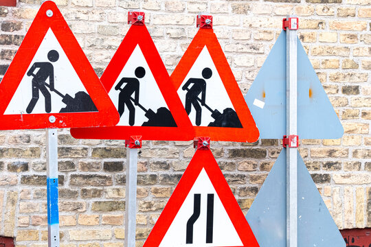 Multiple warning signs with construction symbols on brick wall, urban infrastructure and street signage concept in Copenhagen, colorful and graphic visual.