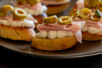 beautiful and delicate party appetizer featuring slices of cheese, mortadella, salami, and green olives
