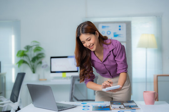 Young beautiful asian businesswoman using calculator while working with financial data and laptop computer in modern office, accounting and analysis concept