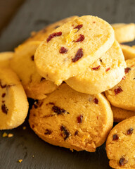 freshly baked orange and cranberry cookies arranged on a dark background