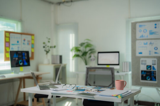 Marketing office desk displaying charts, graphs, laptop, calculator, glasses and coffee cup, suggesting strategic planning and data analysis in a modern workspace