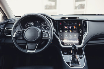 Modern black car interior, leather steering wheel, climate control, large navigation screen, air...