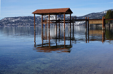 boat house by a pier in  Lake Tahoe, California, USA with mirrot reflection of the mountains in the...