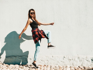 Portrait of beautiful smiling model. Female dressed in summer hipster checkered shirt and jeans....