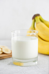 Cold banana milk in a glass on a light table. Traditional Korean drink. Vertical orientation.