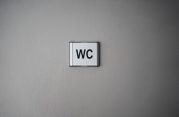 silver toilet sign hanging on the door, toilet sign hanging on the gray door, wc znak na drzwiach, zdjęcie tabliczki w toalecie, srebrne zdjęcie tabliczki wc, wc tabliczka