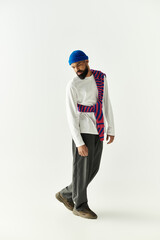 Stylish young man posing in trendy outfit with colorful sweater draped casually