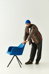 Stylish young man adjusting a vibrant blue chair in a modern minimalist space