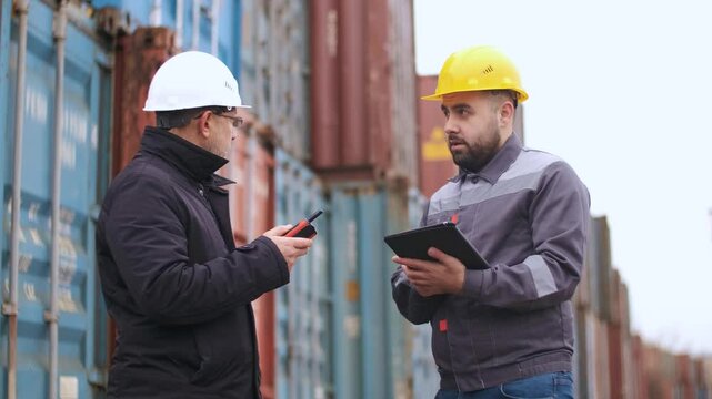 An engineer inspector gives instructions to a port worker before loading containers at the port. Logistics for import and export or shipping career. Port workers hold a meeting before starting work at