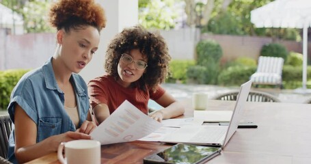 Same-sex lesbian diverse couple discussing financial documents at home with laptop and coffee