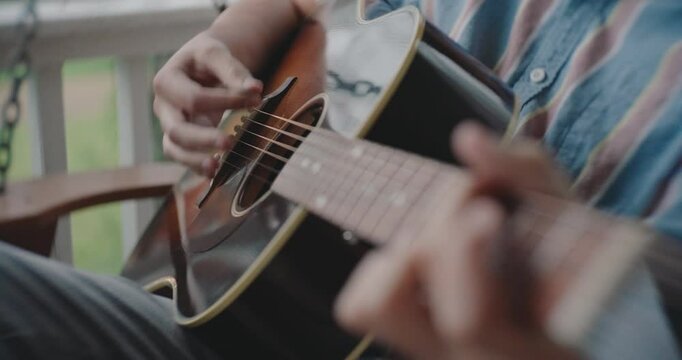 Close up of hands strumming and playing the acoustic guitar 