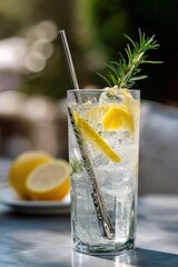 A chilled glass of lemon and rosemary drink, showcasing refreshing herbs in a stylish outdoor setting on a sunny day.