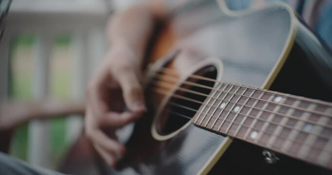 Close up of hands strumming and playing the acoustic guitar 