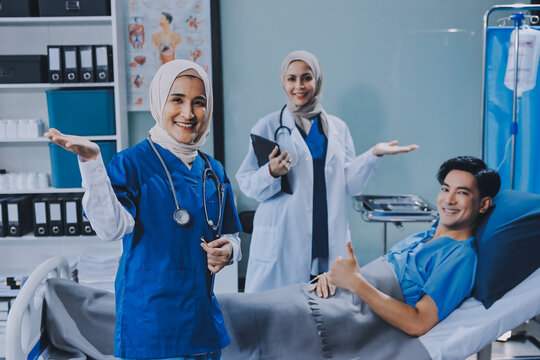A young man lies on a bed in a hospital ward talking with her young Indian doctor. Doctor checking patient's health doctor treating patient, hospital admission of patient - Powered by Adobe
