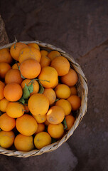 Basket of Fresh Oranges, earthy brown background with copy space, citrus fruits and healthy eating