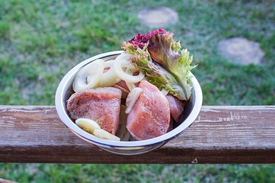 Pork balyk sliced and prepared for barbecue. Marinated meat with onions and herbs in a metal bowl.